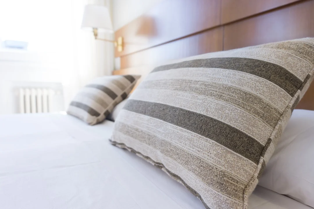 A hotel housekeeper neatly piles fresh towels in a luxurious room setting.